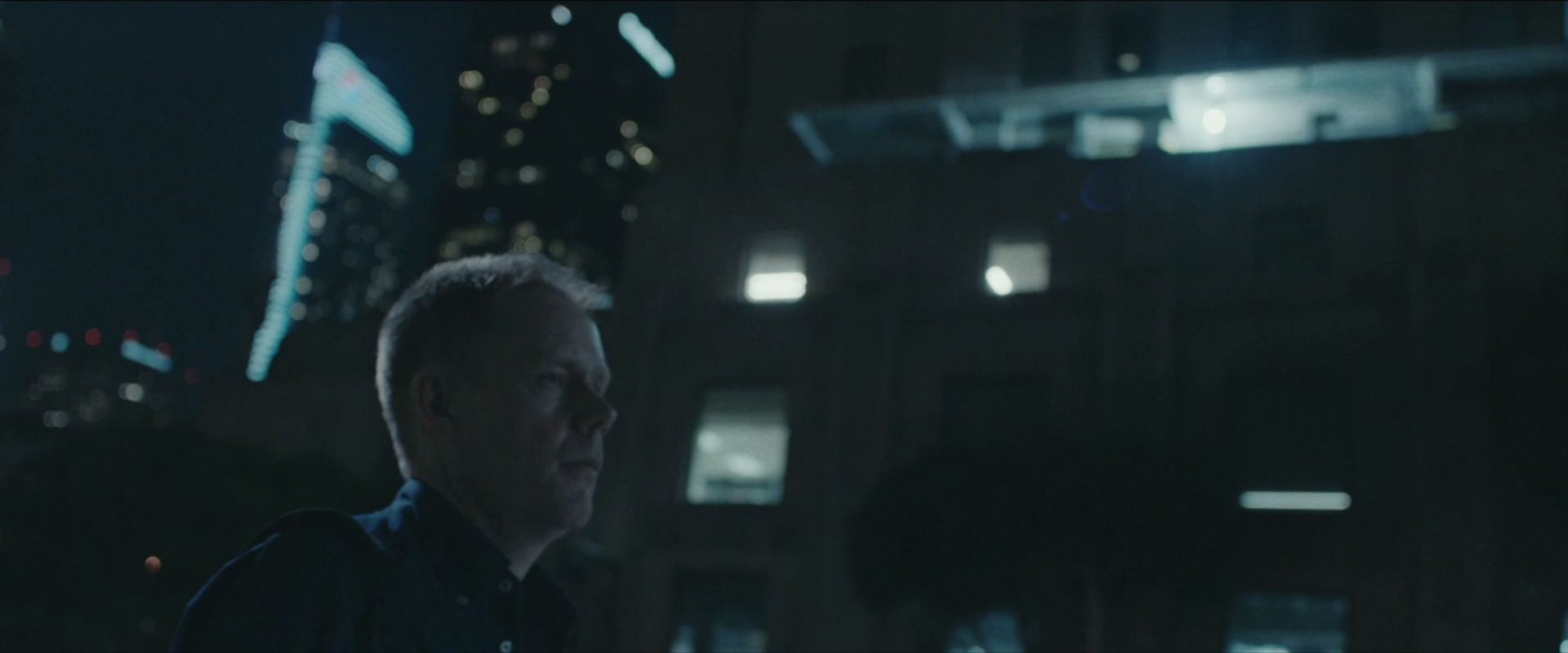 A man looks up at the city at night.